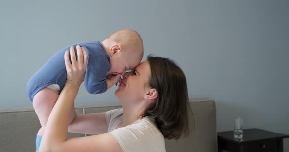 Happy Laughing Mother and Baby, Infant Boy in Arms of Young Beautiful Mother