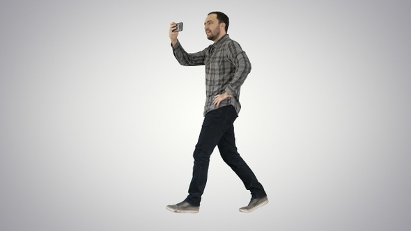 Young man taking photo with smartphone while walking on