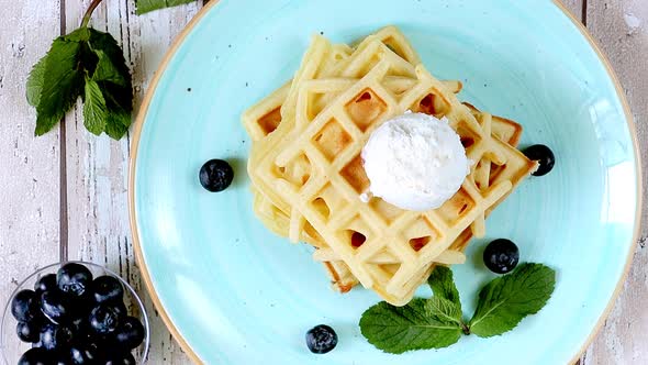 Presentation. Fresh homemade classic Belgian waffles with ice cream, fresh blueberries and mint