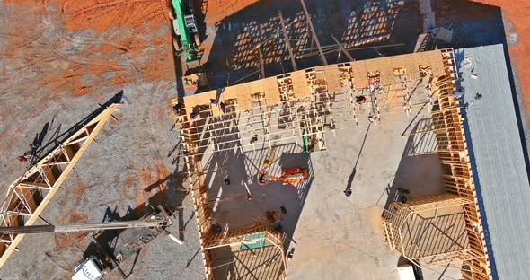 View of New House Construction Interior with Crane Holds Wood Roof Trusses Exposed Framing