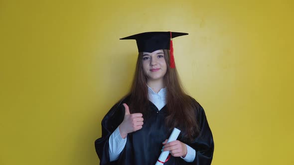 Caucasian Girl Student Shows Finger Up While Staying in Front of Camera with Graduating Diploma in