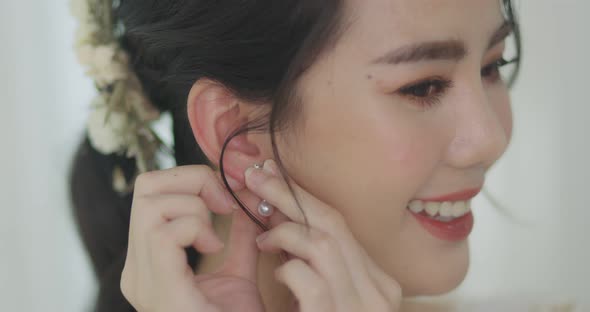 Beautiful Asian Bride In White Wedding Dress Stay Puts On Earrings.