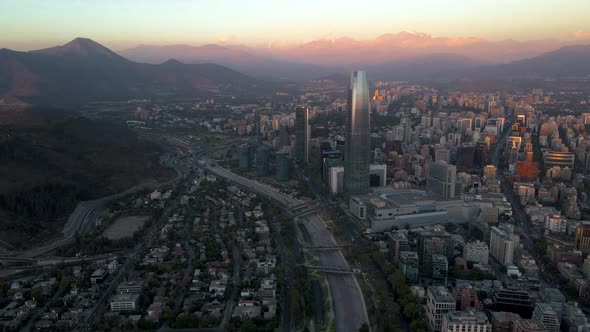 Aerial dolly in of modern Sanhattan skyscrapers, Mapocho river and El Plomo hill in background at bl