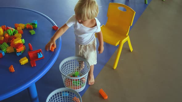 a Small Child Puts a Colored Constructor in a Bucket