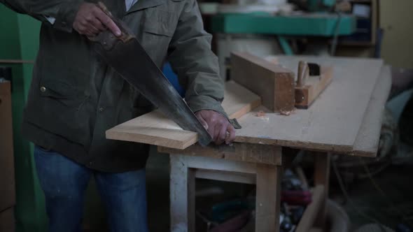 Crop man cutting board with saw