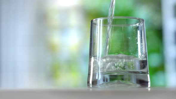 Closeup Pouring Purified Fresh Drink Water From the Bottle on Summer Background