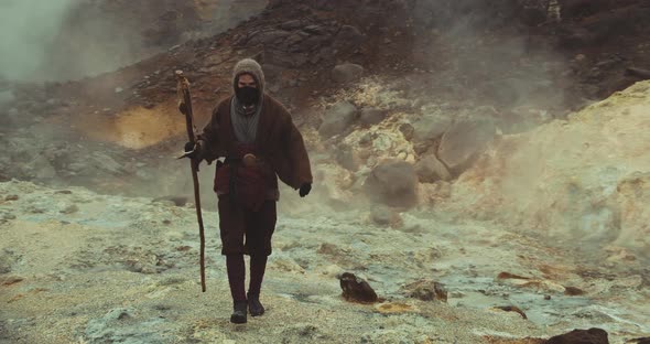 Hooded And Masked Man Walking Through Misty Landscape