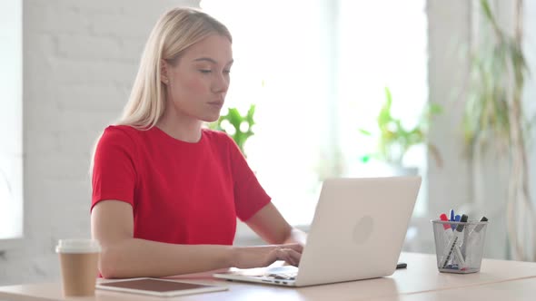 Busy Young Blonde Woman Using Laptop in Office