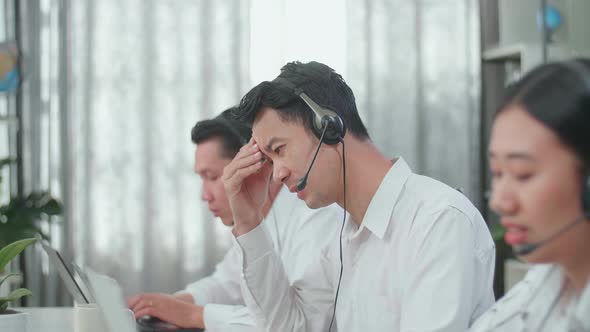 A Man Of Three Asian Call Centre Agents Headache While His Colleagues Are Speaking to Customer