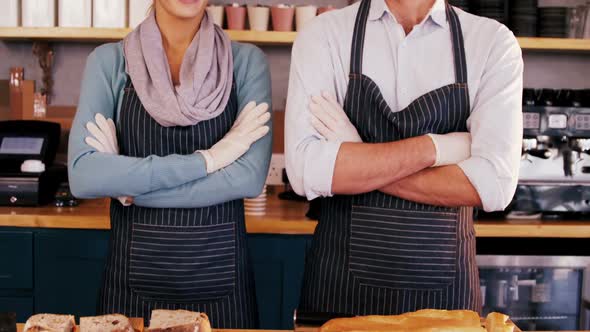 Waiter and waitress standing with arms crossed and smiling at each other