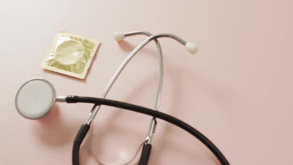 Video of close up of stethoscope with condom on pink background