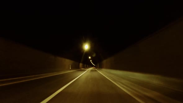 Camera on Car Moving Through Dark Tunnel and Then on Asphalt Countryside Road on Mountainous Terrain