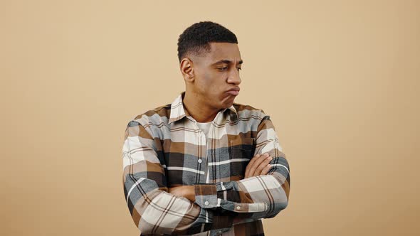 Young Upset African American Man Feeling Offended Pouting Lips and Crossing Arms Beige Studio