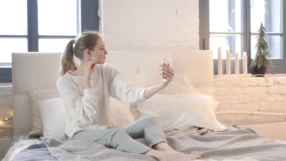 Happy Woman Sitting in Bed Taking Selfie with Phone, Photograph