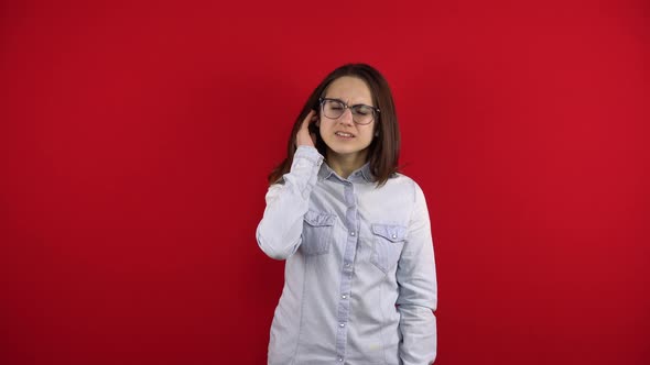 A Young Woman with Glasses Has an Ear Ache and She Holds It in Her Hands