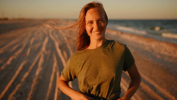 Happy Woman in Tshirt Laughs at Sea on Beach at Sunset