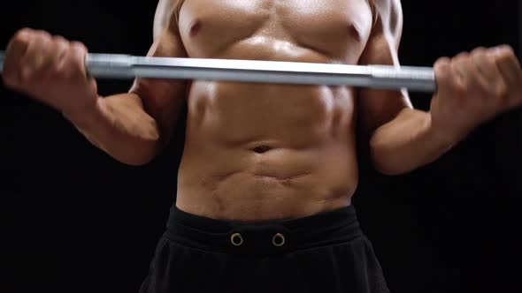 Man is Doing Exercises with a Barbell Training on a Black Background in the Studio