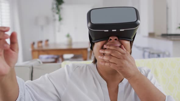 Happy african american senior woman sitting on couch enjoying using vr headset