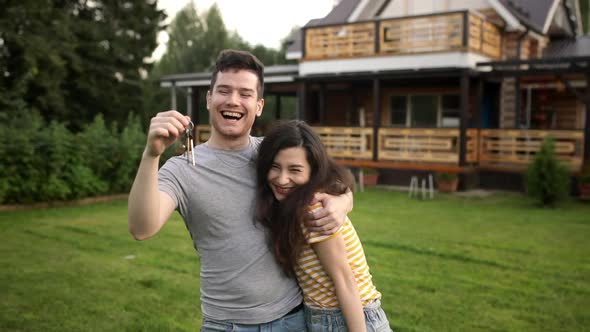 Very Happy Man and Asian Woman is Owners Shake Key and Hug Each Other in Front of Their Newly Bought