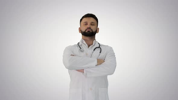 Young Male Caucasian Doctor Standing with Folded Hands on Gradient Background.