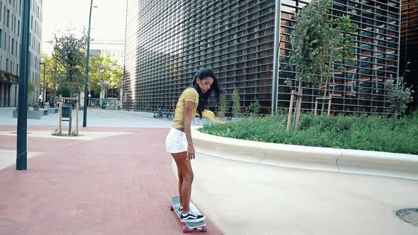 Pretty Athletic Girl Rides a Longboard in Modern City