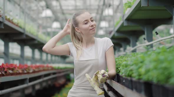 Smiling Pretty Girl Taking Off Gloves and Looking at Camera. Portrait of Positive Young Caucasian