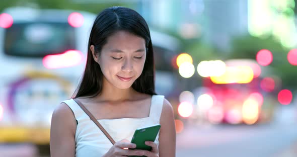 Young woman use of mobile phone in the city at night