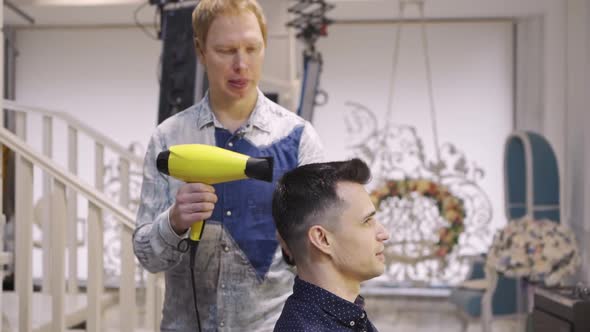 Hairdresser Dries Hair Dryer Brunette Man in a Barbershop