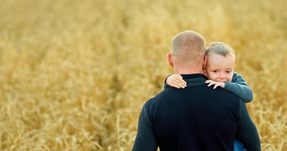 Father Carries His Son in His Arms the Son Looks Over the Shoulders of the Dad and Hugs Him By the