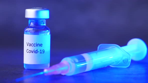 Close Up of Coronavirus Vaccine and Syringe on Black Background