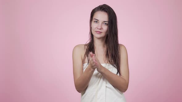 Woman in Towel Applies Oil To Wet Hair After Shower Isolated on Pink Background