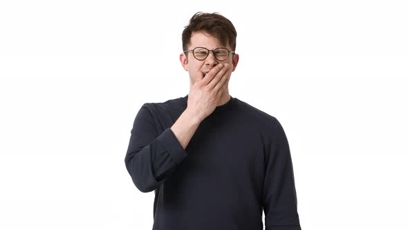 Portrait of Overworked or Sleepy Man 20s Wearing Black Sweatshirt and Glasses Yawning and Covering