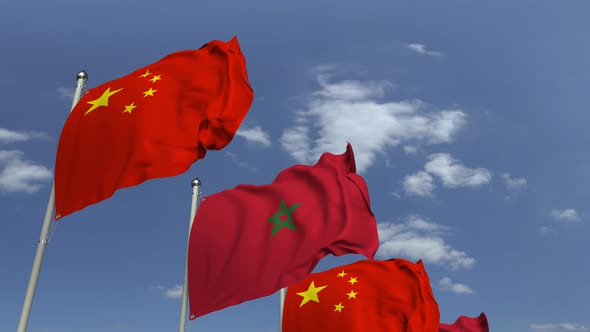 Waving Flags of Morocco and China on Sky Background