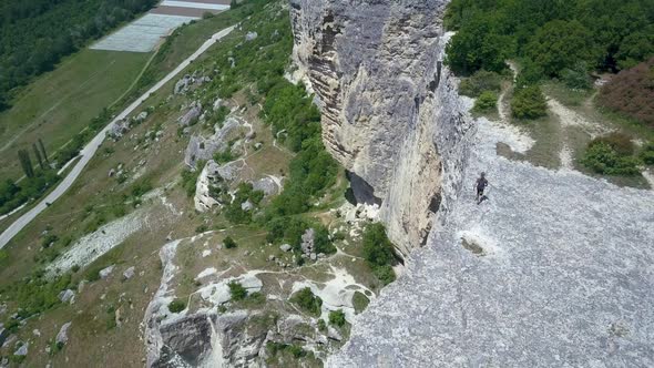 Athletic Man Tourist Wanders Along the Edge of the Mountain and Explores the Area. Panorama of the