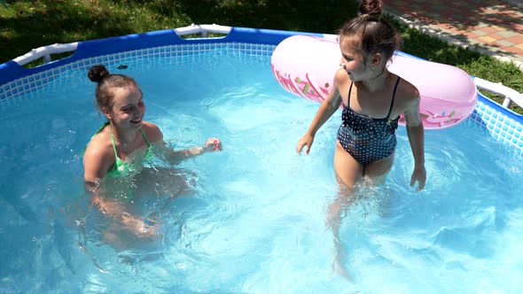 Happy Girls Swim in Outdoor Leisure Pool on Sunny Summer Day Swimming