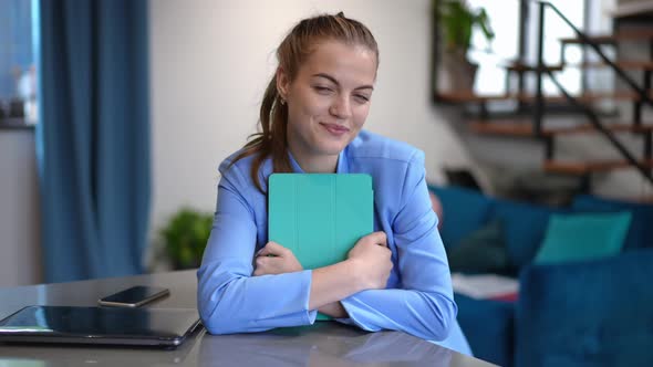 Beautiful Slim Young Businesswoman Looking at Camera Smiling Sitting Indoors with Tablet and Laptop