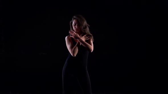 a Young Energetic Woman in a Black Suit in a Studio on a Black Background Dancing, Moving and Posing