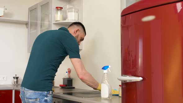 Man Cleaning Stove with Detergent at Home Kitchen