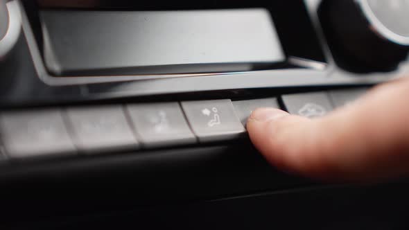 Close up to finger press a button on the car's dashboard to adjust a seat.