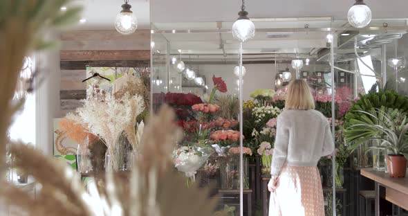 Attractive Girl Florist Entering The Fridge With Flowers.