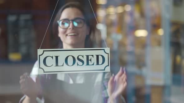 Smiling Woman Turning Open Sign at Shop Glass Door for Welcome Customer Into Coffee Shop