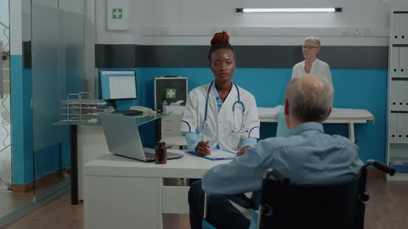 Patient with Disability Sitting at Desk for Checkup with Medic