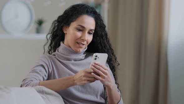 Young Female Attractive Arabian Muslim Girl Woman in Hijab Sit on Sofa Smiling Islamic Lady Texting