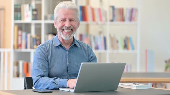 Old Man with Laptop Smiling at the Camera 