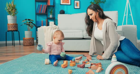 Caring Beautiful Women Spends Free Time with Child on Carpet Toys are Scattered Around Them