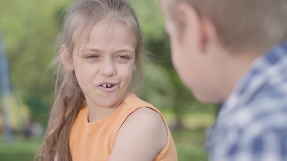 Portrait of Cute Boy and Girl Sitting in the Park, Talking and Having Fun. A Couple of Happy