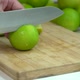 Hand Slicing fresh Lime With Knife On Wooden Board In Kitchen - VideoHive Item for Sale