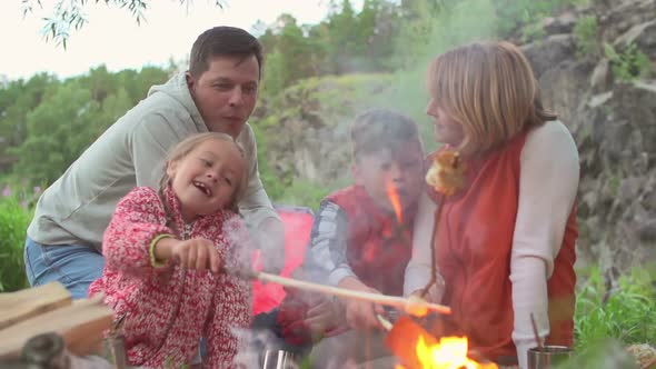 Family Roasting Bread Over Campfire