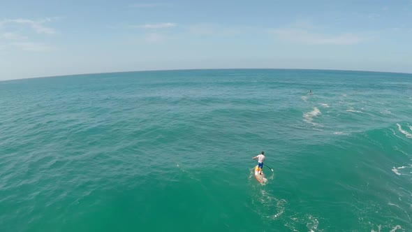 Aerial view of a man sup stand-up paddleboard surfing in Waimea, Hawaii