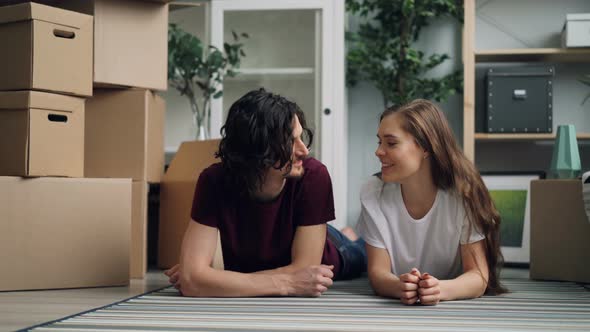 Young Woman Giving Key To Husband Then Kissing on Floor in New Apartment